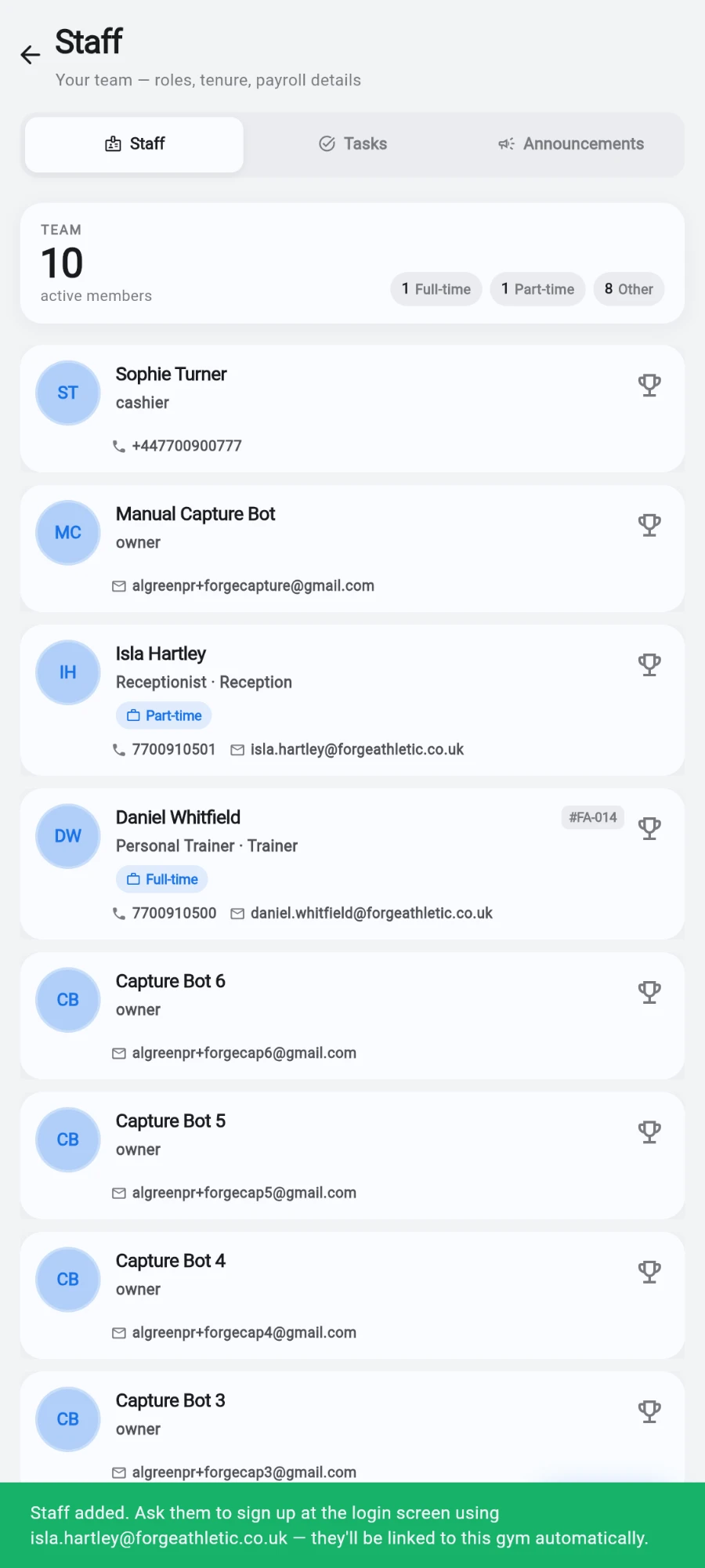 The Staff tab after saving, showing the team list with the new Isla Hartley (Receptionist · Reception, Part-time) and Daniel Whitfield (Personal Trainer · Trainer, Full-time) records, and a green confirmation bar reading 'Staff added. Ask them to sign up at the login screen using isla.hartley@forgeathletic.co.uk — they'll be linked to this gym automatically.'