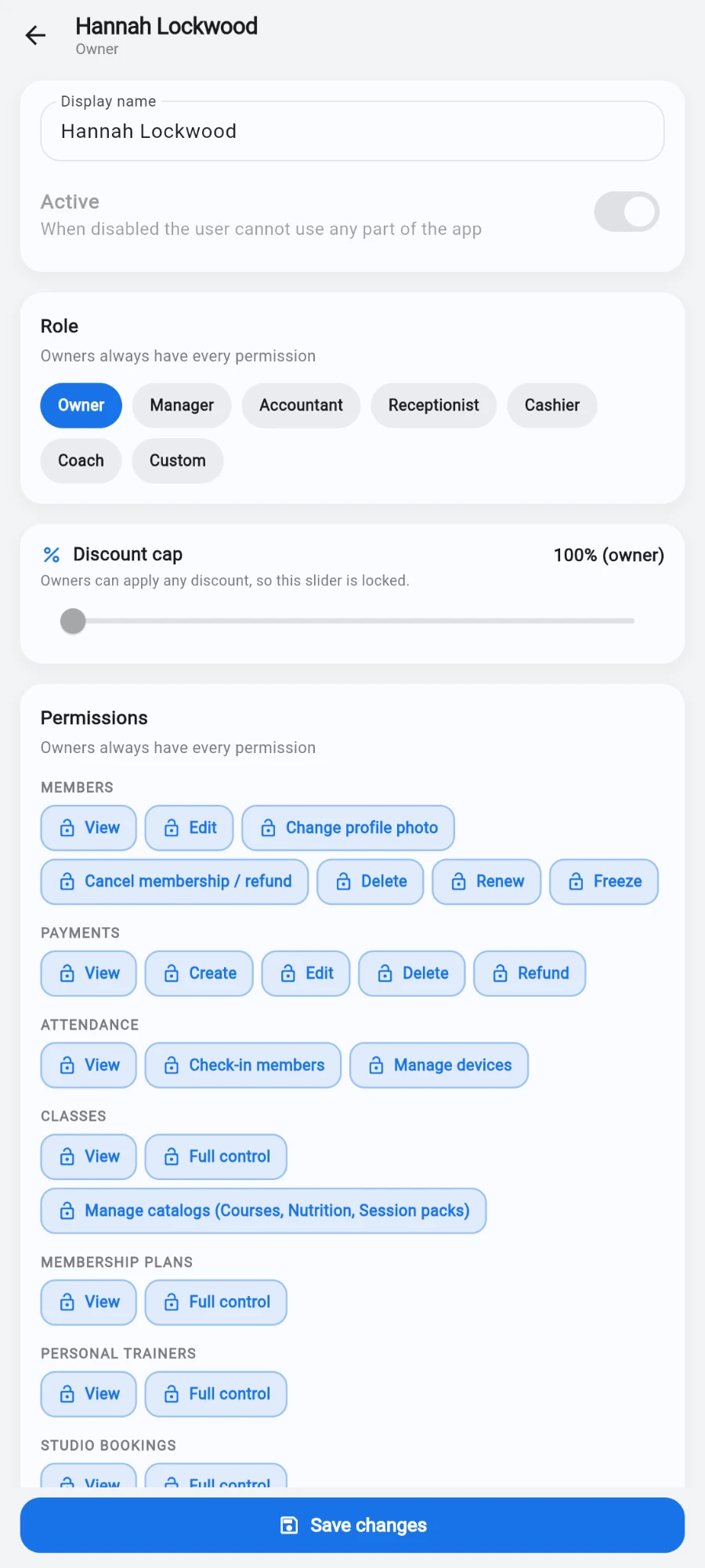 The user editor for Hannah Lockwood (Owner): a Display name field and an Active switch, a Role card with Owner selected next to Manager, Accountant, Receptionist, Cashier, Coach and Custom, a Discount cap card reading '100% (owner) — Owners can apply any discount, so this slider is locked', and a Permissions card of per-action chips grouped into MEMBERS, PAYMENTS, ATTENDANCE, CLASSES, MEMBERSHIP PLANS and PERSONAL TRAINERS, with Save changes pinned at the bottom