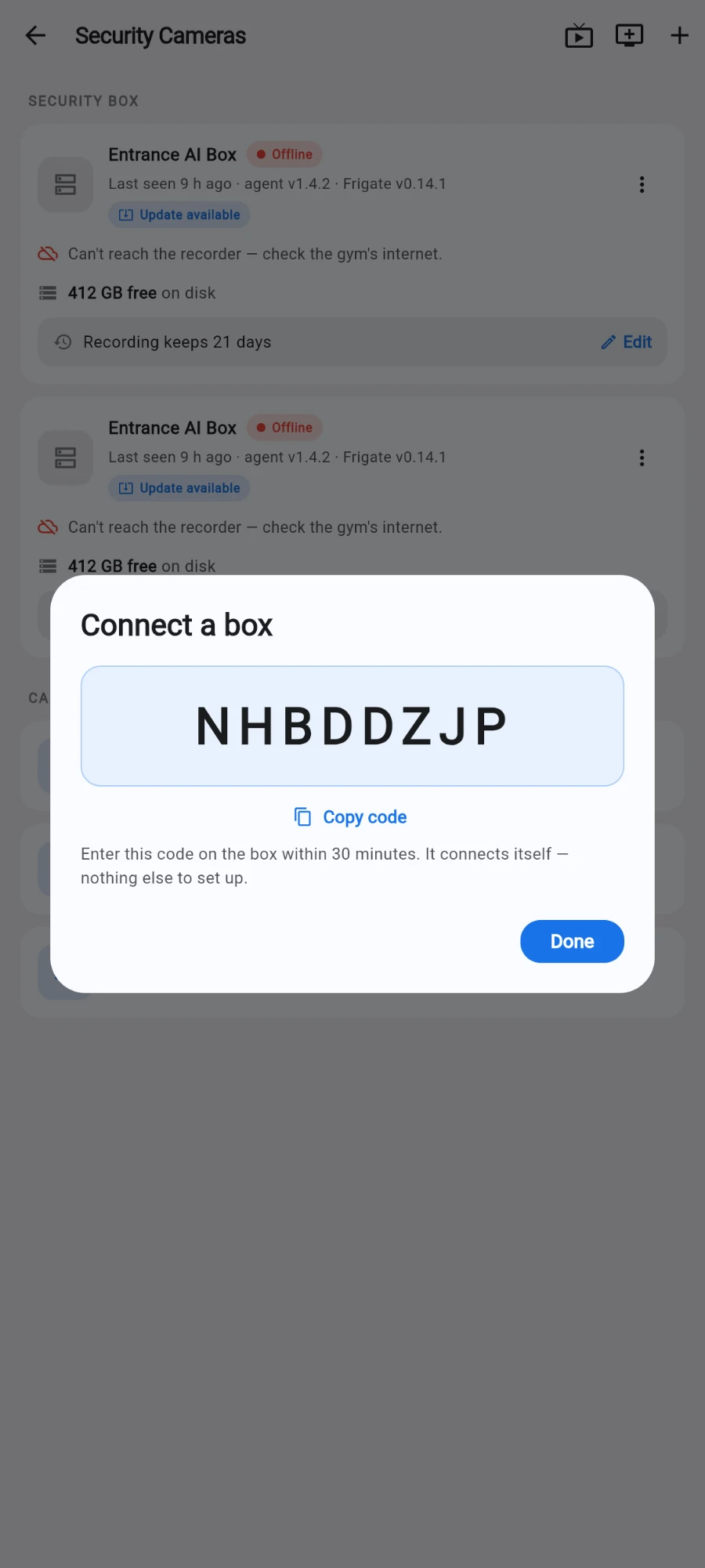 The Connect a box dialog on the Security Cameras screen, showing the 8-character claim code NHBDDZJP, a Copy code link, the note “Enter this code on the box within 30 minutes. It connects itself — nothing else to set up.” and a Done button