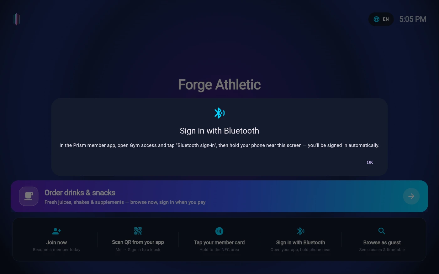 The Bluetooth sign-in explainer over the Forge Athletic welcome screen: a Sign in with Bluetooth panel reading — In the Prism member app, open Gym access and tap Bluetooth sign-in, then hold your phone near this screen and you will be signed in automatically — with an OK button, above the sign-in strip where Tap your member card sits next to Sign in with Bluetooth.